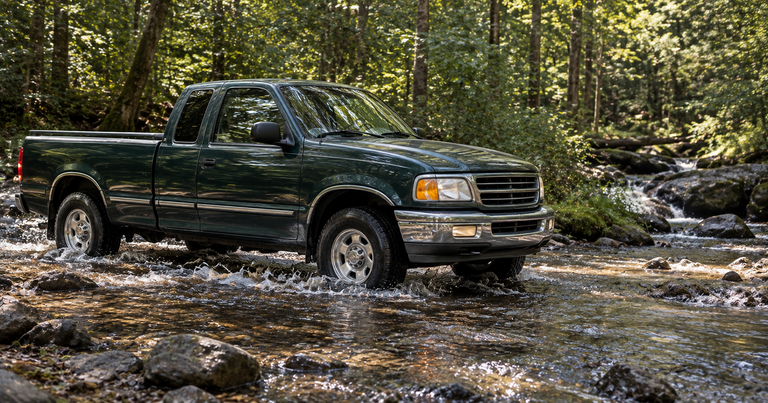 Dark green 1990s Ford F-150 crossing a forest creek, classic Ford truck alternators